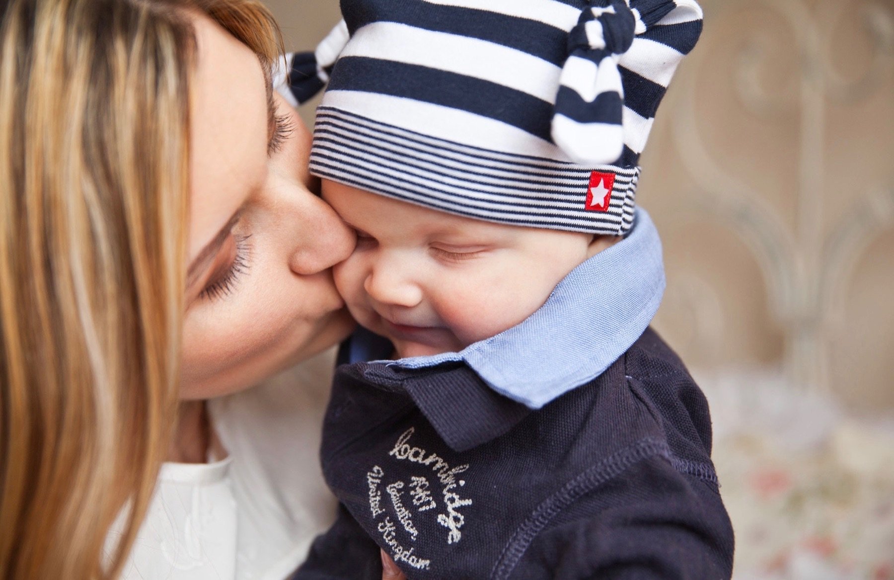 A mother kisses her infant child on the cheek.