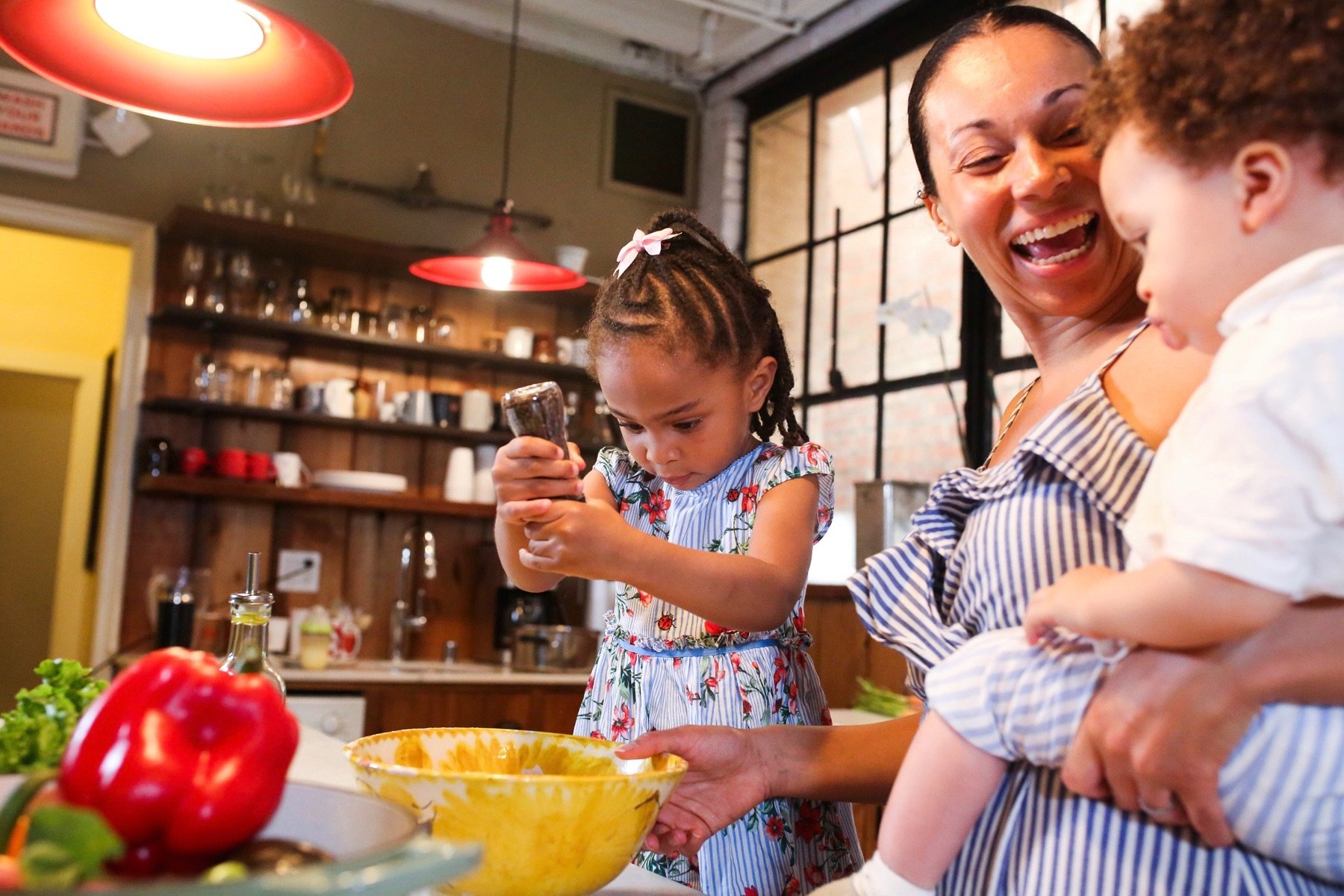 A mother and two children make dinner together in their kitchen.