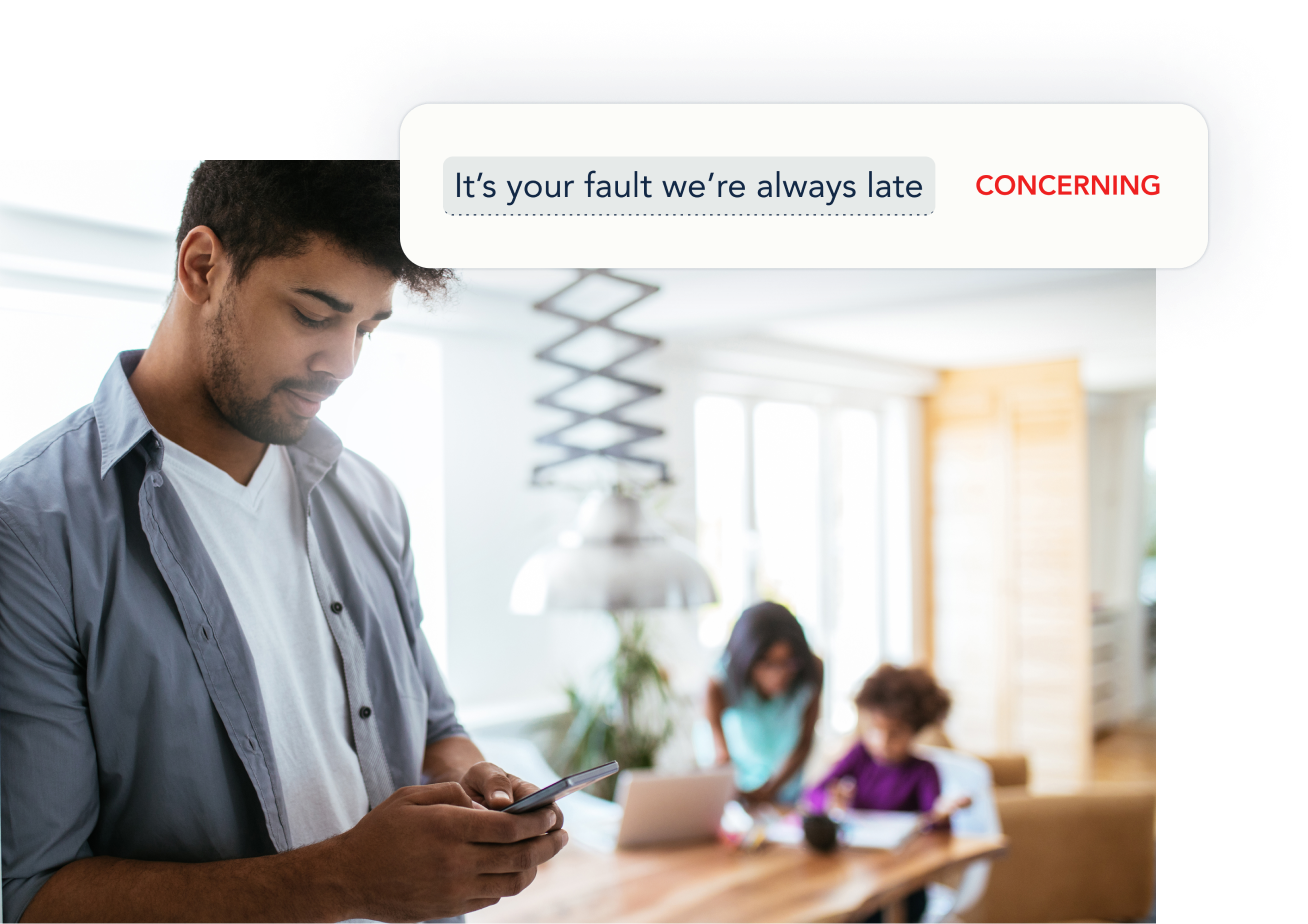 A man types a text message on his cell phone as his family sits at a table far from him.