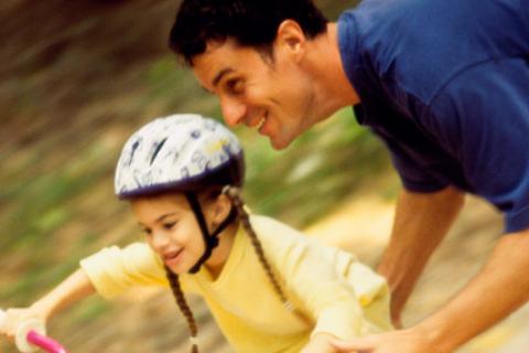 Father teaching daughter how to ride a bike