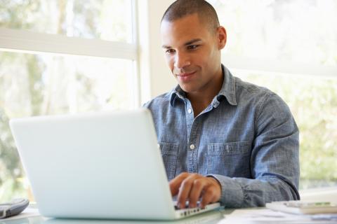 Man sits at table while using a laptop