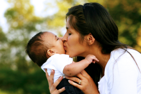 Mother holding and kissing infant