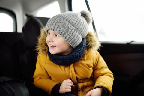 Bundled-up little boy in the backseat of a car, on his way to a parent's house.