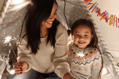 Mother and daughter celebrate a holiday together and play with sparklers.