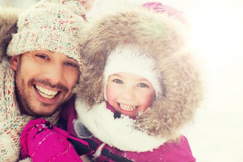 Father and daughter laughing outside during the winter, bundled up