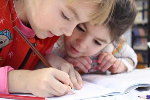 Two children draw together with colored pencils.