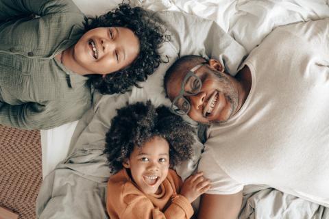 Two kids and their dad lay together in bed.