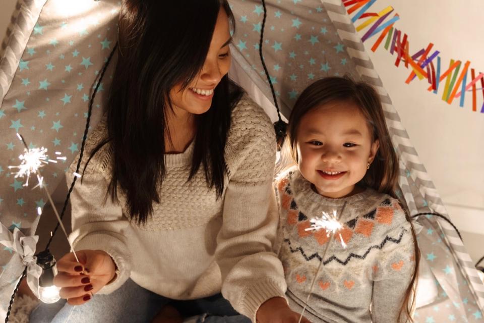Mother and daughter celebrate a holiday together and play with sparklers.