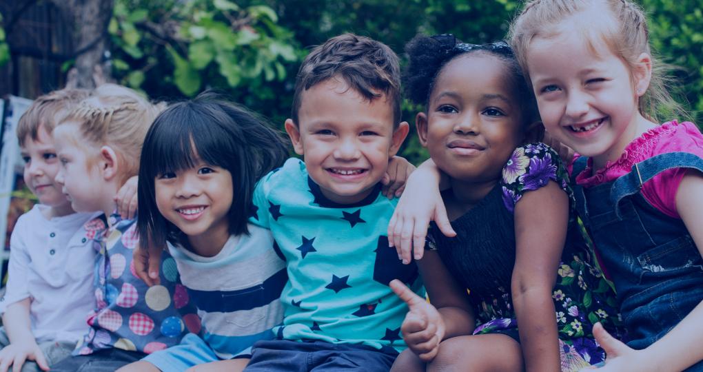 A group of children sit together and smile.