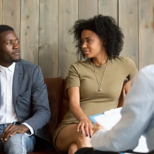 Two parents sit on couch while working with a mediator