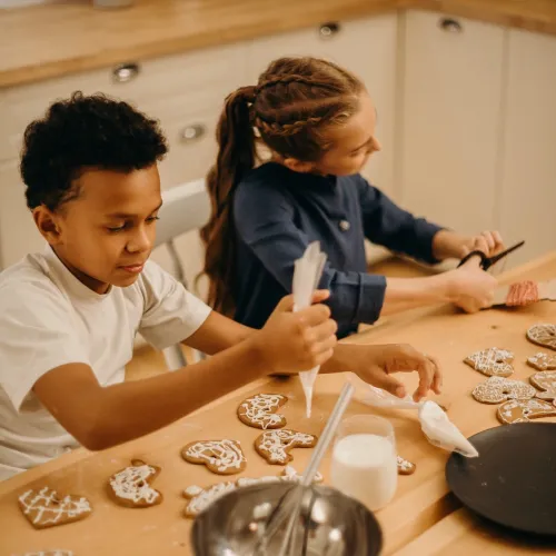 Two kids decorate cookies in the kitchen
