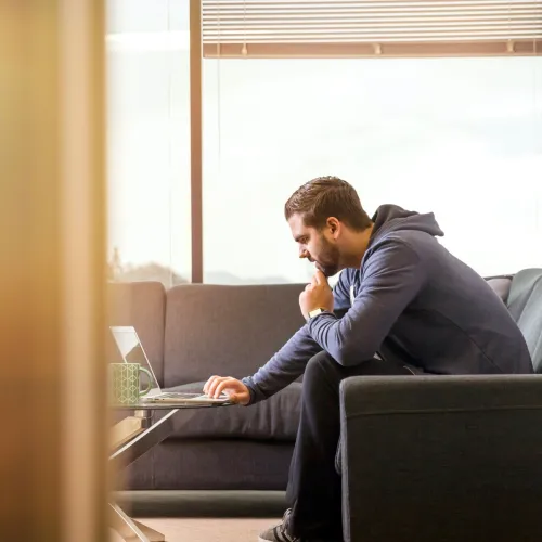Man sits on the couch while using his computer.