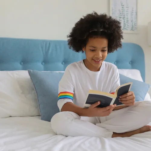 A young girl reads quietly in bed.