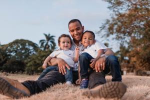 A father and his sons sit together on a sunny day.