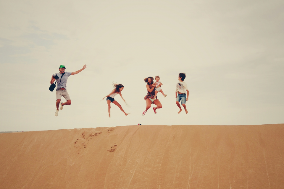 Family jumps in unison at the top of a sand dune