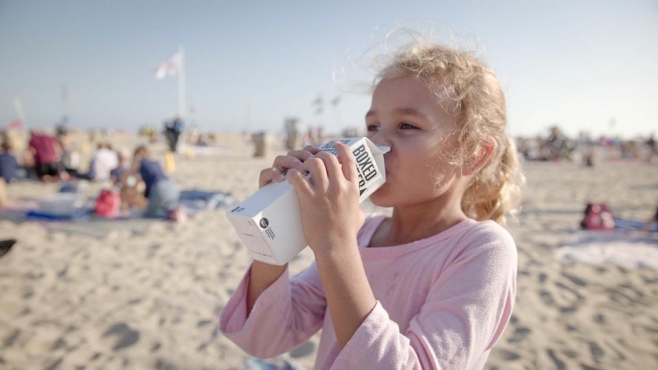 A young girl enjoys a cold water on the beach.