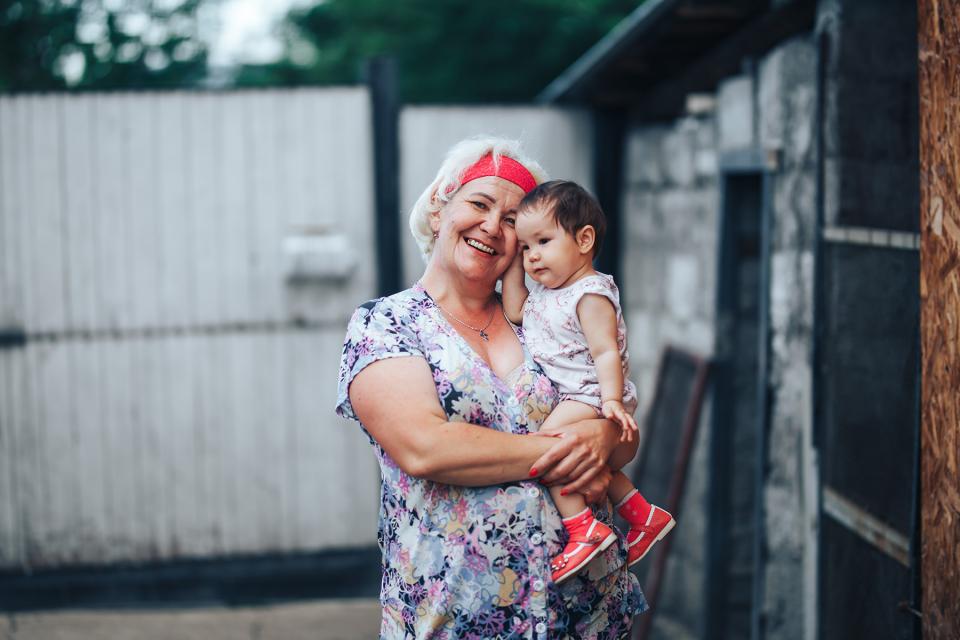 Smiling grandmother holds her grandbaby outside.