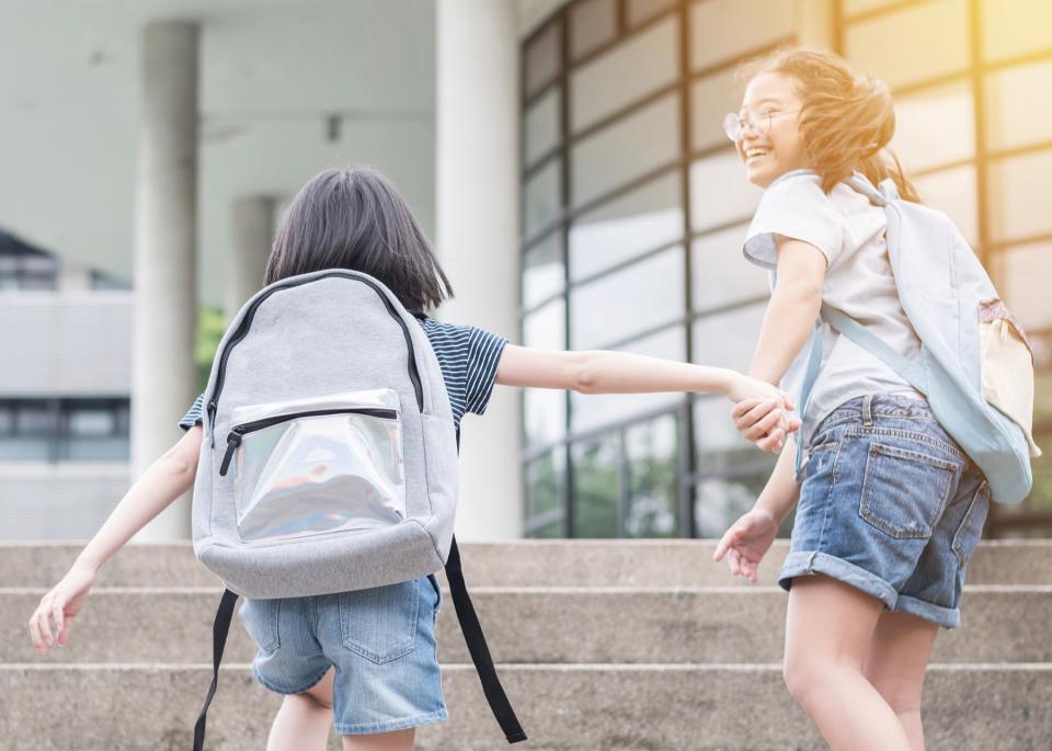 Two girls run up the stairs at their school.