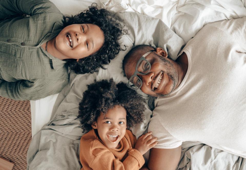 Two kids and their dad lay together in bed.